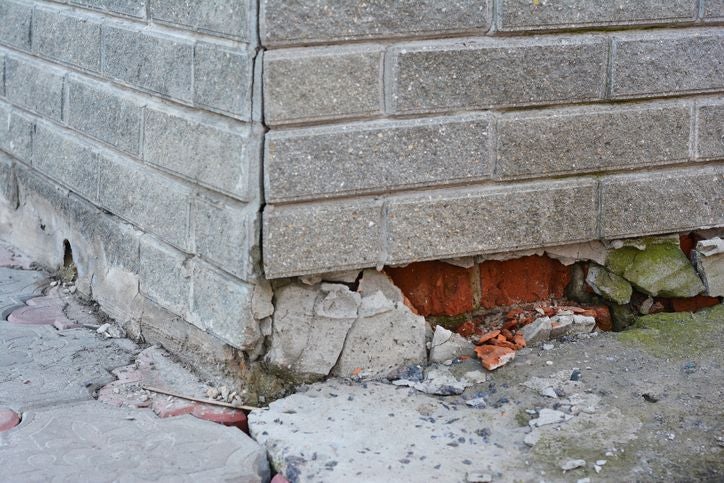 Cracked building foundation and damaged corner wall